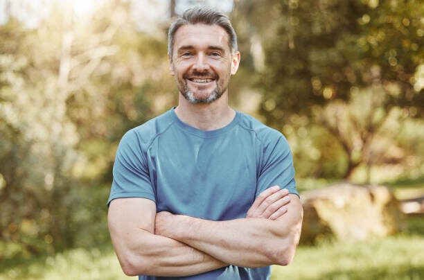 Senior, fitness and portrait of man with arms crossed in a park happy with workout, running or results. Exercise, face and elderly male runner smile in forest for training, workout or body challenge